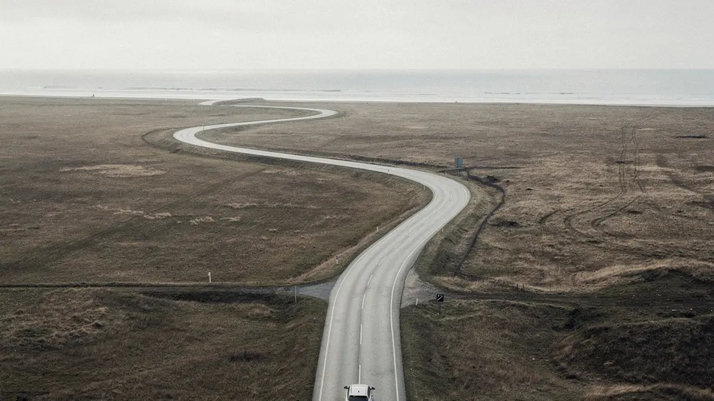 Vue large d'une voiture sur une route sinueuse, suggérant la planification du kilométrage annuel sans aucun repère chiffré.